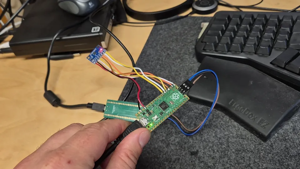 The prototype IMU on the bench next to a monitor showing its live orientation and sensor plots in Rerun